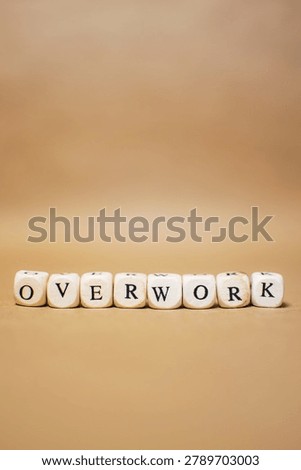 Vertical image of the word OVERWORK made from letter cubes on beige background. Concept of employee burnout, excessive workload, workplace pressure and mental exhaustion.