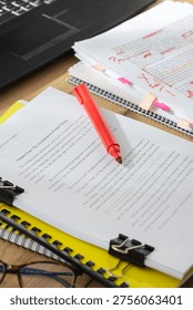 Vertical image of workspace with documents, clips and notes during proofreading and editing of written content