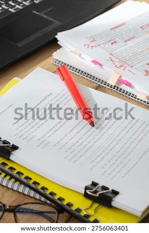 Vertical image of workspace with documents, clips and notes during proofreading and editing of written content