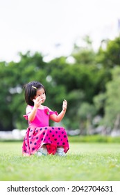 Vertical Image. A Young Girl Is Stumped Alone After Losing A Soccer Match, A Child Sits On A Soccer Ball In The Middle Of A Green Lawn.