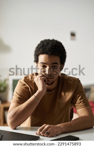 Vertical image of young man in melancholy sitting at desk with pensive expression