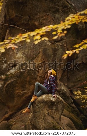 Vertical inspiring wanderlust shot of travel hipster woman relaxing in the nature, sits on stone in old woods with mossy boulders. concept of people love for nature and planet earth