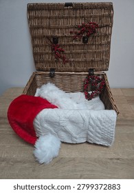 Vertical Interior View of a Festive Wicker Hamper with a Santa Hat and Cable Knit Blanket