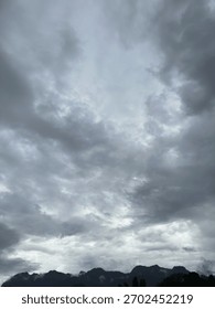 Vertical landscape with dramatic dark storm clouds covering the sky above a misty mountain range.