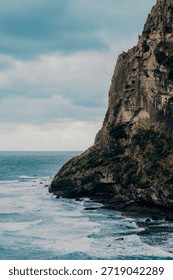 Vertical landscape view of a dramatic volcanic cliff face rising from the blue ocean. Scenic coastal view of Seongsan Ilchulbong (Sunrise Peak) in Jeju Island, South Korea. UNESCO World Heritage nature site.