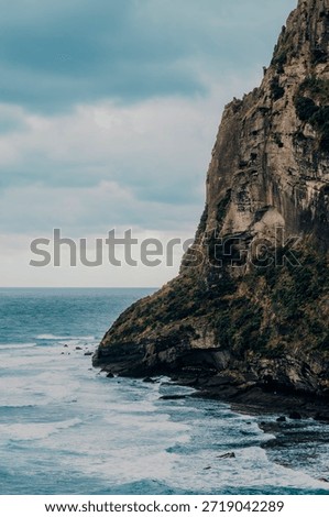 Vertical landscape view of a dramatic volcanic cliff face rising from the blue ocean. Scenic coastal view of Seongsan Ilchulbong (Sunrise Peak) in Jeju Island, South Korea. UNESCO World Heritage nature site.