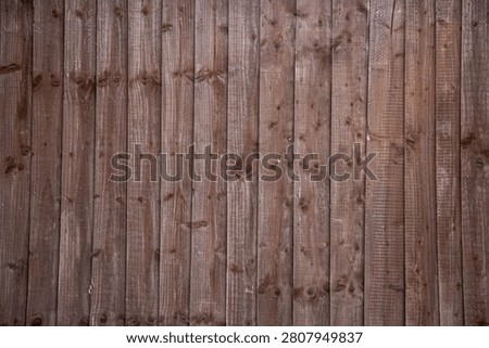Vertical lap feather edge timber garden fence panel featuring a dark brown, weathered finish and natural wood grain. The traditional treated timber fencing provides durable boundary screening and long-lasting protection against the elements, making it a popular choice for residential gardens and outdoor landscaping.