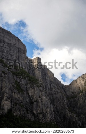 Vertical low angle shot looking up at the iconic Preikestolen Pulpit Rock square cliff soaring high above Lysefjord in Rogaland, Norway.