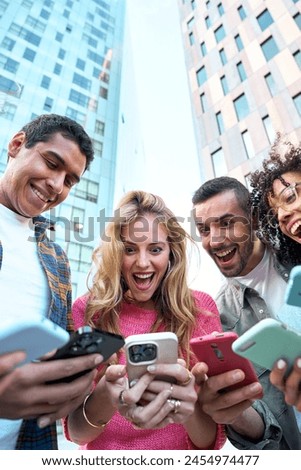 Vertical low angle view of a group of young jaw dropping mixed race people with mobile phones. Excited students using their technological devices. Concept of enterprising, friendly, app, millennial