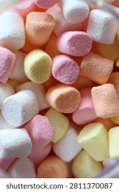Vertical macro close up of colorful mini pastel marshmallows background texture.