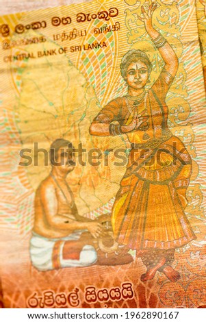 Vertical macro detail of the reverse side of 100 Sri Lankan Rupees LKR bill banknote (Sri Lanka Dancers series) showing a traditional mridangam drummer and bharatanatyam dancer