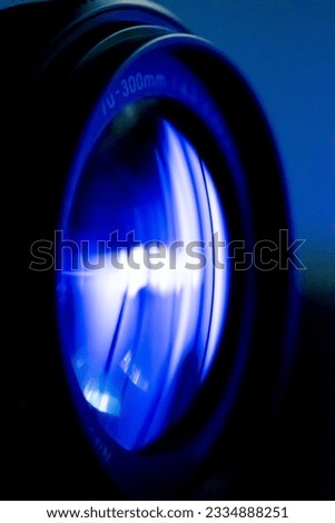 A vertical macro shot of a 70-300mm camera lens over a blue background