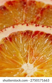 Vertical macro of a sliced blood red Sicilian Cara Cara orange. Sharp focus on the textured rind and adjacent red pulp. Beautiful color gradient from red to yellow. Soft blurry citrus background.