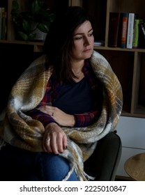 Vertical Mature Thoughtful, Depressed, Disappointed, Sad Mature Brunette Woman, Covered By Blanket, Sit In Chair In Against Bookcase. Sick Season, Illness And Disease Pandemic. Burnout On Sick Leave