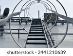 Vertical metal staircase to the roof of the hangar. Staircase surrounded by a protective frame.