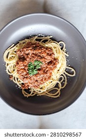 A vertical minimalistic layout presenting a fresh hot serving of savory spaghetti pasta topped with rich beef bolognese herb sauce.