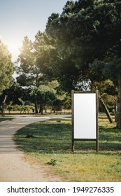 A Vertical Mockup Of A Map Placeholder In A Public Park; Blank Advertising Billboard Near A Footpath; A White Empty Template Of An Outdoor Info Poster In A Rural Area Surrounded By Coniferous Trees