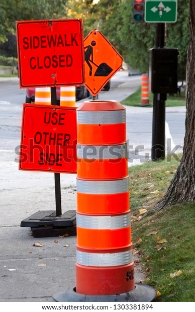 Vertical of orange cones and construction signs \
on a street corner in Montreal, Quebec, on an overcast but bright\
day in October.