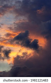 Vertical panorama with dramatic sunset sky with dark rain clouds and vibrant orange yellow red colors against a blue sky. Weather conditions and climate concept. Abstract background wallpaper poster.