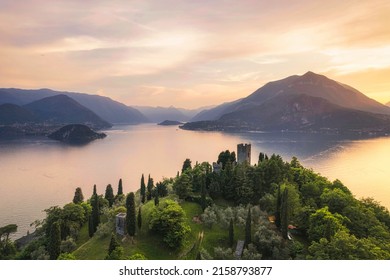 Vertical panoramic aerial view of Vezio Castle with Varenna village and mountains in background during summer sunset. Drone shot in Como lake. Varenna, Italy