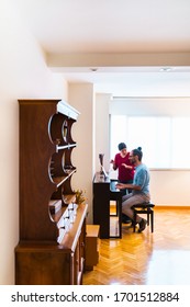 Vertical panoramic view in the house of a mature man practicing musical lessons. Learning and teaching music concept. Piano lessons at home. Female teacher giving a keyboard piano class to student.