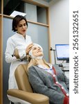 Vertical photo of an adult female psychiatrist is placing a transcranial magnetic stimulation device on a young female patient to treat mental illness in a medical clinic. TMS concept.