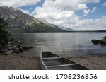 Vertical photo of a canoe on the beach of a mountain lake ready to be paddled