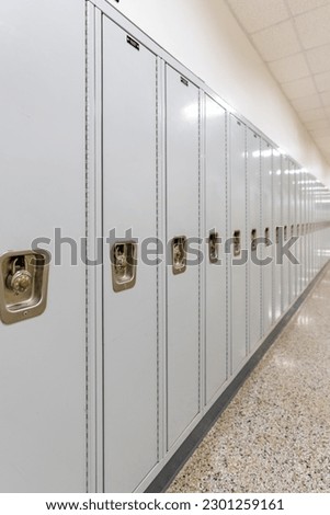 Vertical photo of an empty middle school or high school hallway with gray student lockers
