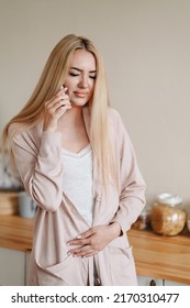 Vertical Photo Of A Girl Calling On A Mobile Phone. The Woman Blinks In Pain. Call Doctor. Concept Women's Health, Lifestyle. Gynecology.