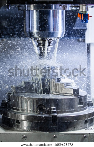 Vertical\
photo of industrial wet milling process in 5-axis cnc machine with\
coolant flow under pressure and freezed\
splashes