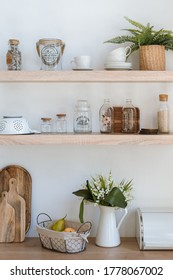 Vertical photo of kitchen with kitchenware supplies on wooden shelves, cutting boards, houseplants, flowers and modern furniture in minimalist interior style - Shutterstock ID 1778067002