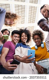 Vertical photo. Low angle view of a group of young teenagers holding cell phones. Concept of technology, connection.