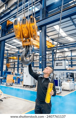 Vertical photo of a male operator using an industrial crane in a logistics factory