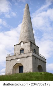 Vertical photo of the Obelisk in Killiney Hill Park, Co. Dublin, Ireland. Historic structure with square base, recessed arches on each side with seats and with viewing platform and cone on the top.