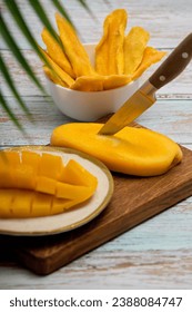 Vertical photo of a plate with sliced juicy pulp of tropical sweet mango. Healthy fruit ripe snack of ripe mango and slices of sweet candied fruits. 