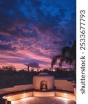 A vertical photo of the purple monsoon sunset in the Sonoran desert of Tucson, Arizona, over a kiva fireplace Santa Fe style.