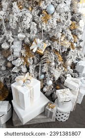 Vertical photo of rich and trendy style christmas tree with xmas presents decorated in whie, gold and silver colors.