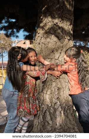 vertical photo of three orphaned latin girls playing with a tree in an outdoor park in latin america bolivia