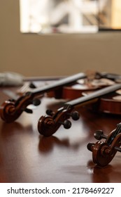 Vertical Photo Of Three Violins In Musical Instrument Repair Workshop