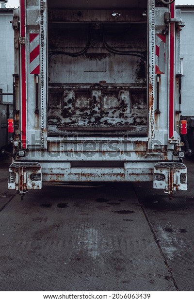 Vertical photo of a truck from the back with an\
open trunk.