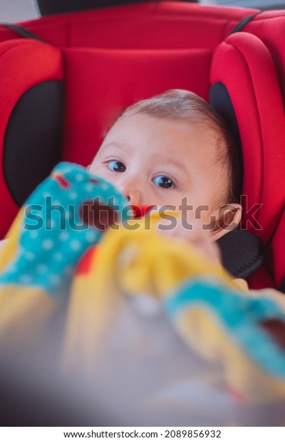 Vertical Photo Of Young Asian Girl in Her Car\
seat with a blanket keeping her\
warm
