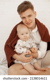 Vertical Photo Of Young Smiling Man Dad Holding Baby And Toys, Weekend Activity. Tender And Caring Parenthood. Close Up