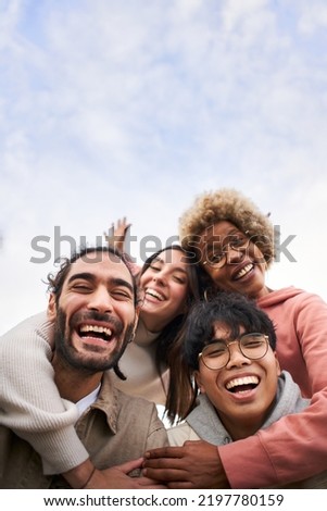 Vertical pic of Group of young people looking at the camera outdoors. Happy smiling friends hugging. Concept of community and youth lifestyle