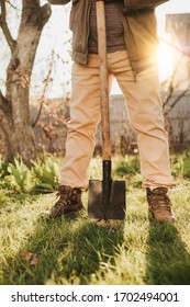 Vertical Picture Cut View Of Man With Shovel In Hands. Gardening Garden On Backyard Outside. Green Fresh Grass Outside. Sunny Beautiful Spring Day