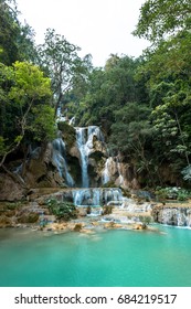 Vertical picture of the main waterfall of Kuang Si Falls in Laos. Colorful water and tropical vegetation.