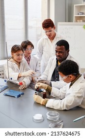 Vertical portrait of African American teacher demonstrating science experiments to group of children in chemistry lab at school