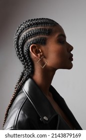 Vertical portrait of African young woman with braids posing on white wall.