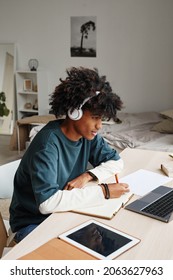 Vertical Portrait Of African-American Teenage Boy Studying At Home Or In College Dorm And Using Laptop