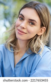 Vertical Portrait Of Beautiful Adult Woman, Sitting In Blue Collar Shirt Outdoors, Smiling And Looking Cute At Camera. People Concept