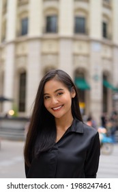 Vertical portrait of beautiful Asian businesswoman smiling outdoors in city street
